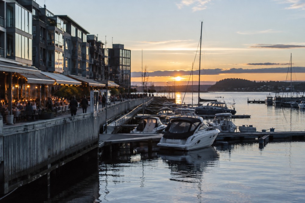 Aker Brygge waterfront restaurants lit up at dusk with moored boats
