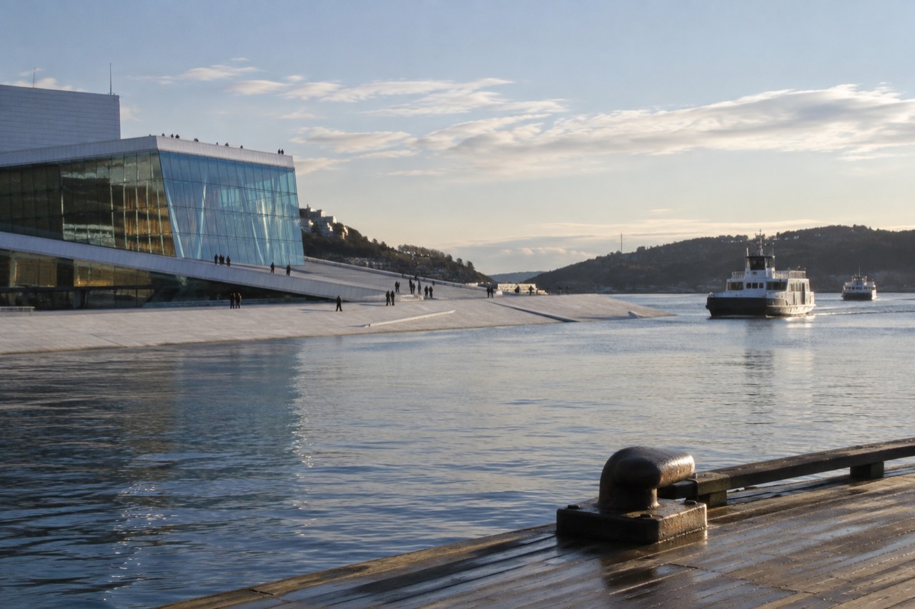 Oslo harbor waterfront with the Opera House roof and fjord boats in morning light