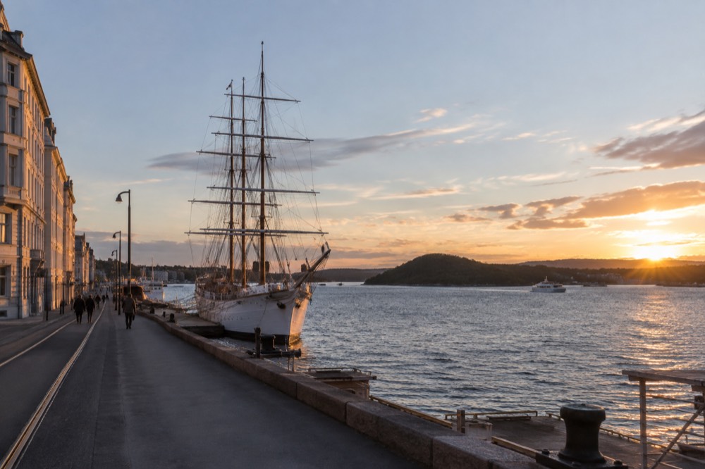 White wooden sailing ship moored in the Oslofjord with forested islands behind