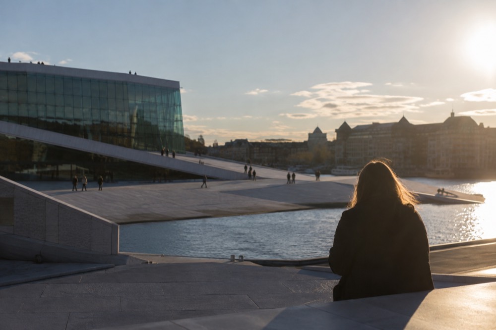 Angular white marble roof of a waterfront opera building sloping down to the sea