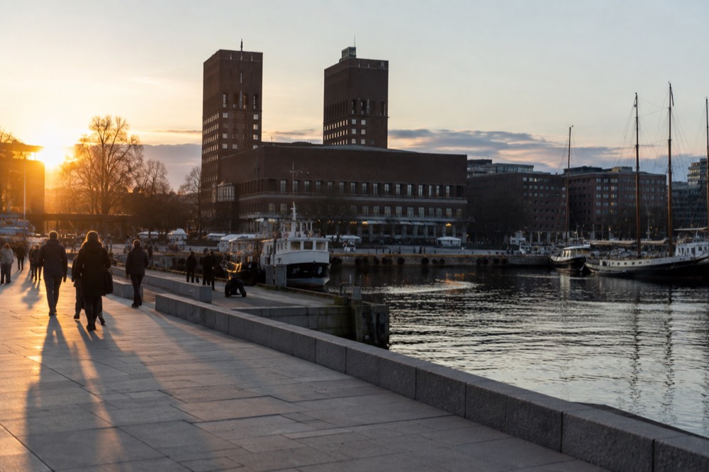 Oslo harbor at dusk with city hall towers and moored boats