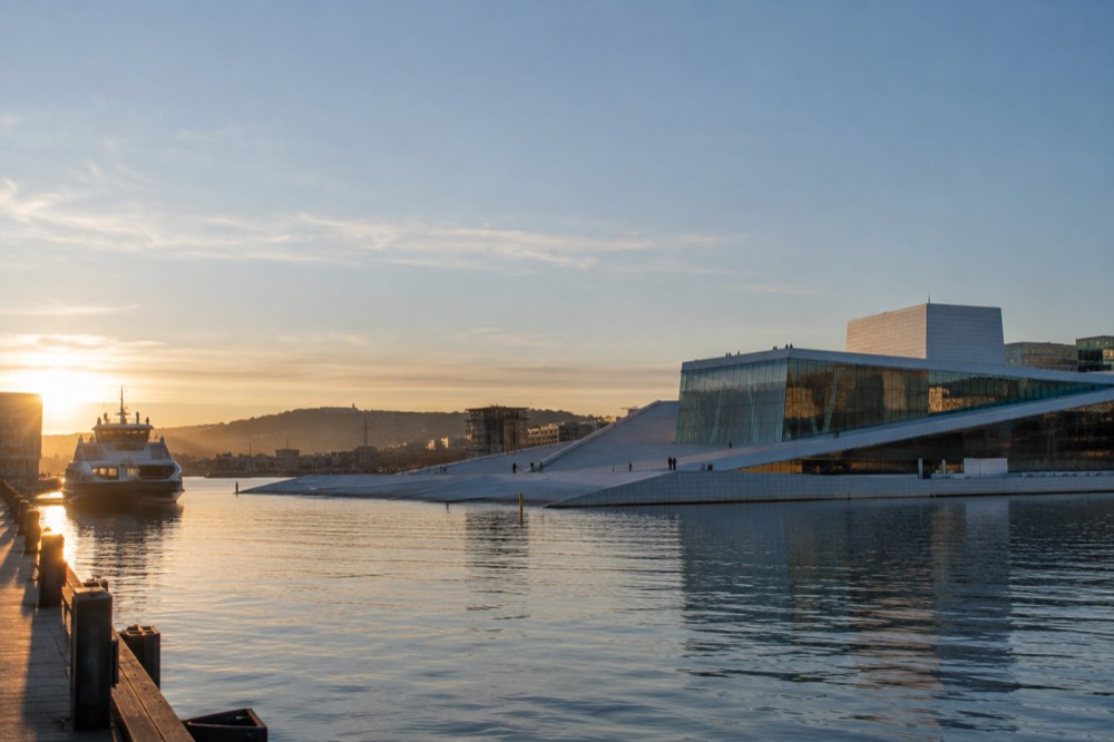 Oslo harbor at sunrise with the Opera House and ferry piers along the water