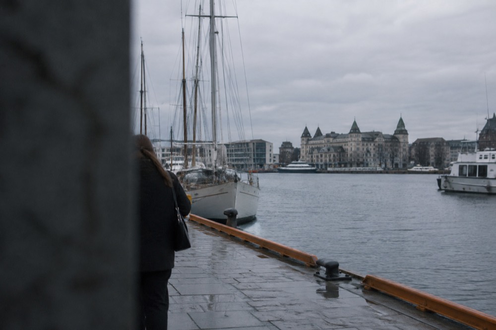 Harbor front in central Oslo with moored boats and stone buildings along the water