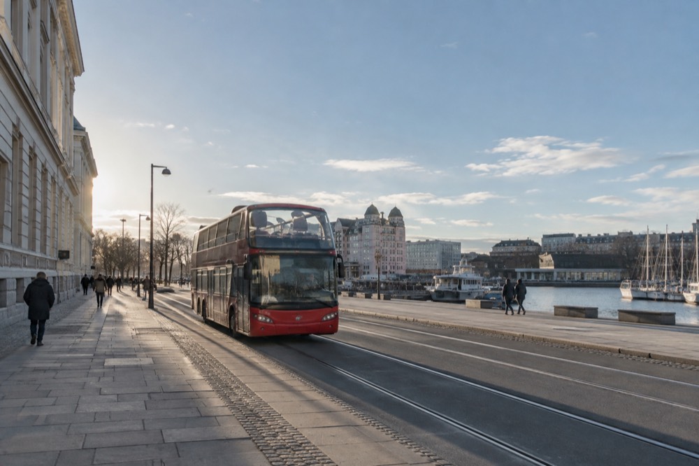 Hop-on hop-off style sightseeing bus parked near a Oslo waterfront street