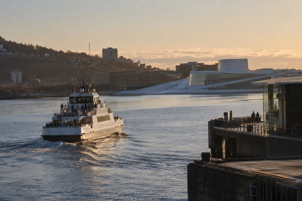 Passenger ferry departing a city pier with museum buildings visible across the water