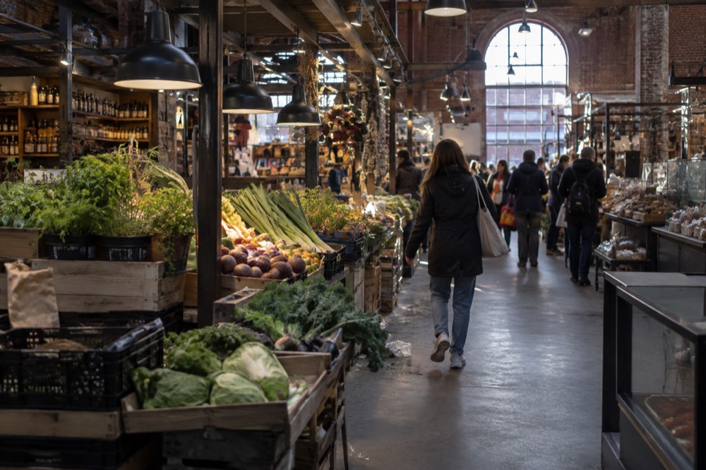 A food hall interior with market stalls under old industrial brick vaults