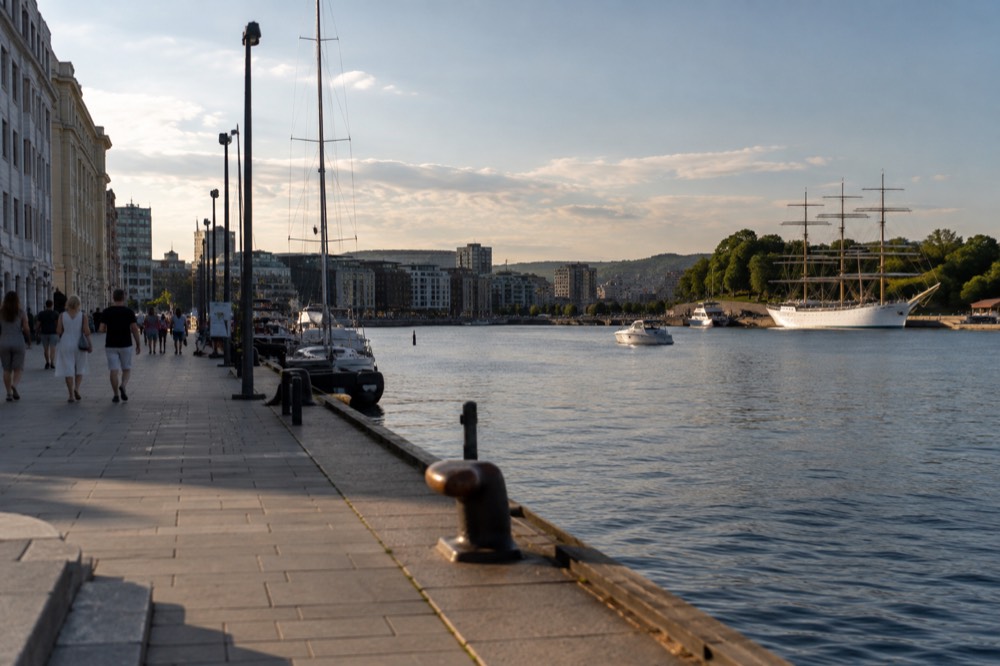 A white sailing ship and small boats on calm water in the Oslo harbor