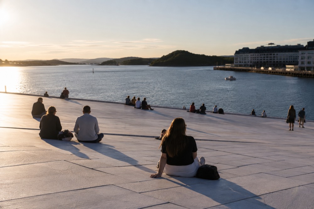 The marble roof of the Oslo Opera House sloping down toward the water in evening light