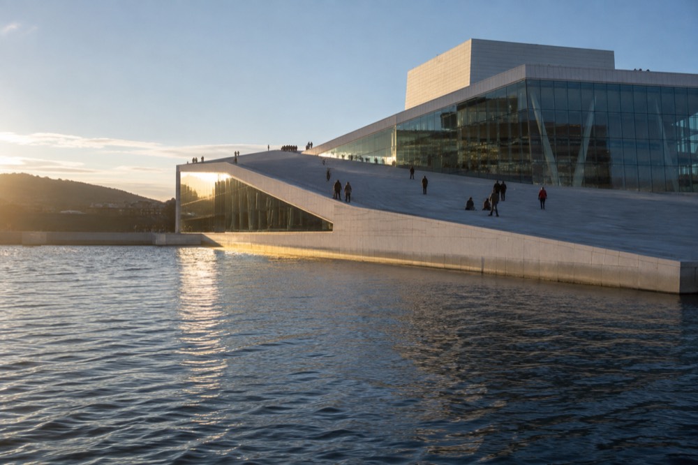The sloping marble roof of the Oslo Opera House seen from the water at midday