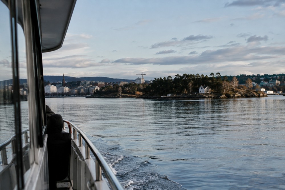 A silent electric boat cruising past forested islands in the inner Oslofjord