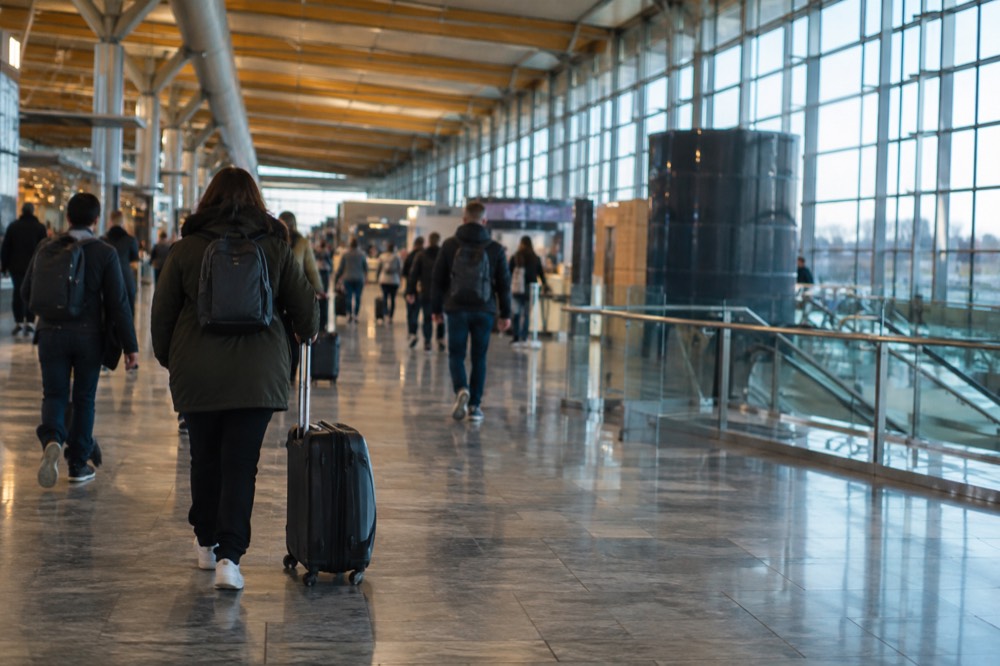 Travelers with a wheeled bag walking through the departures hall at Oslo Airport