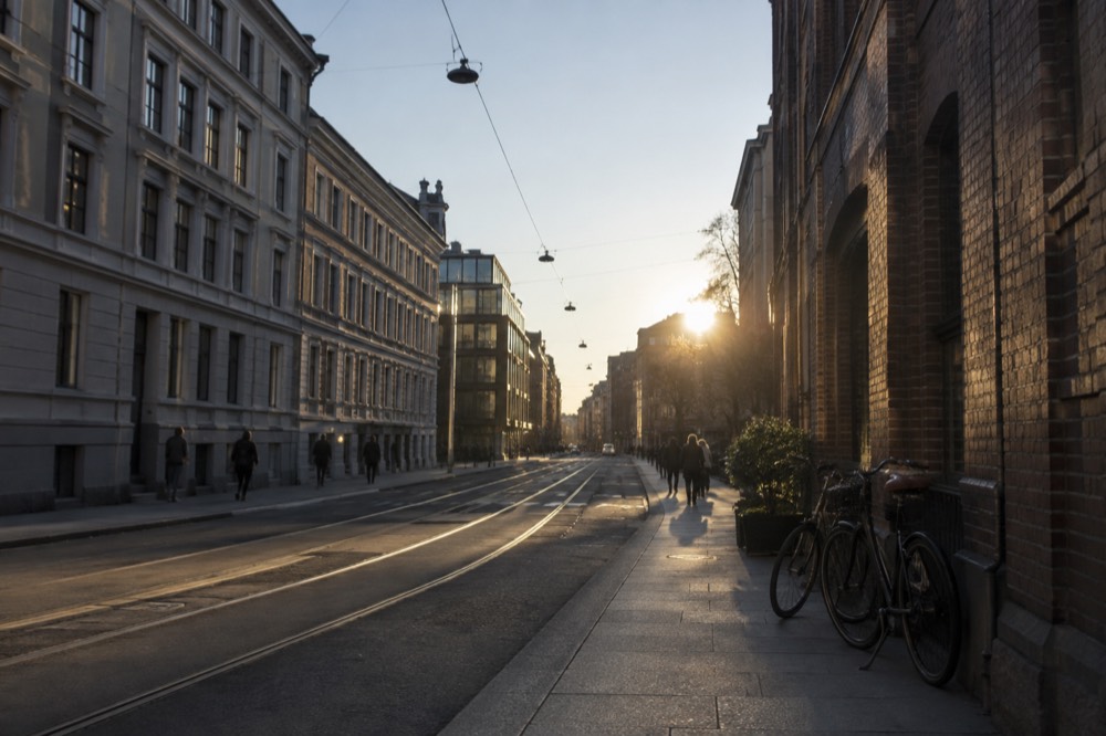 A quiet Oslo street with brick buildings and bicycles leaning against a wall