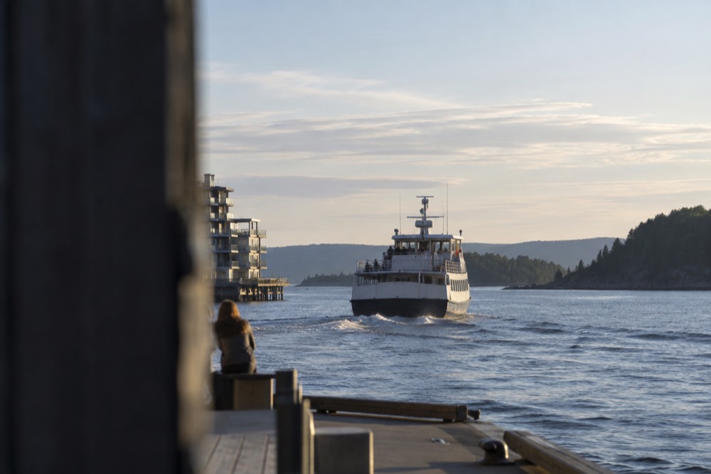 A ferry pulling away from a city pier toward forested islands