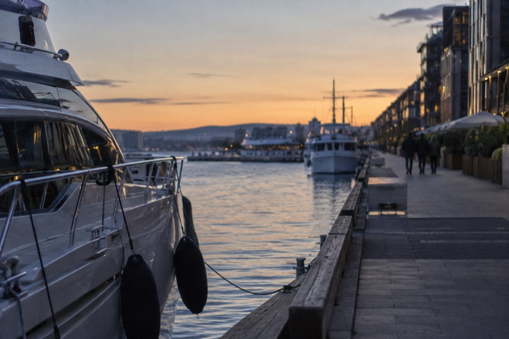 Golden evening light over Oslofjord boats and waterfront promenade