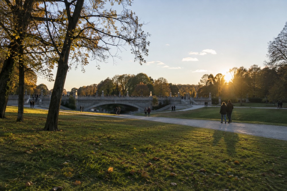 Stone bridge in Vigeland Park seen across open parkland with visitors walking the paths