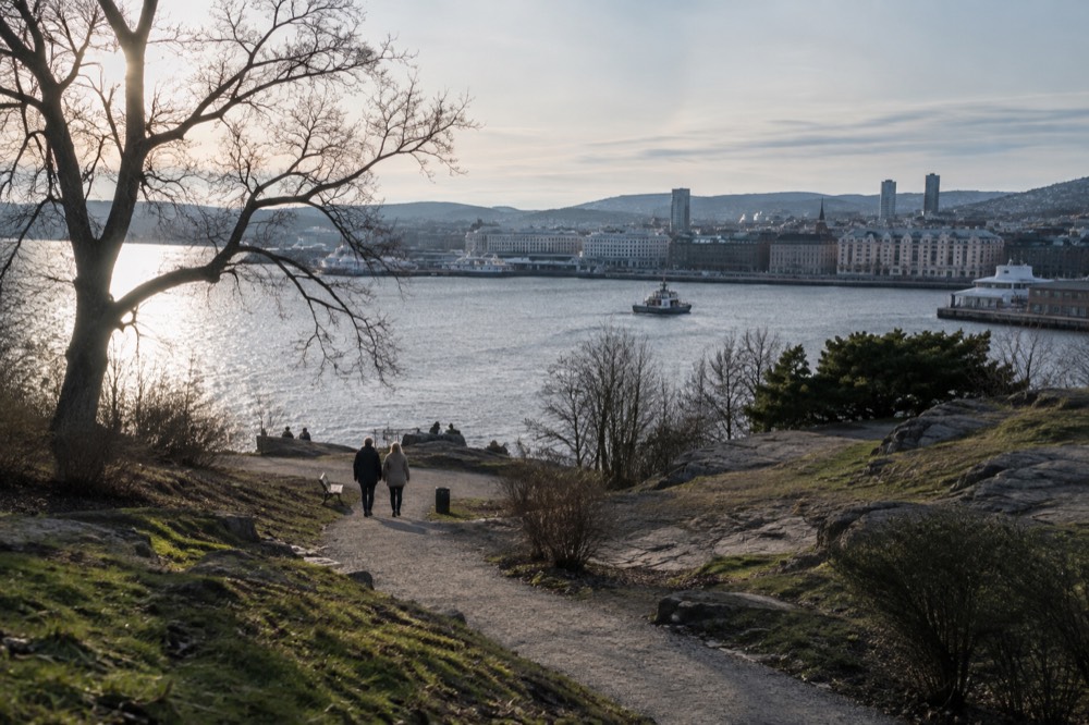 Path through a green Oslo island with the city skyline across the water