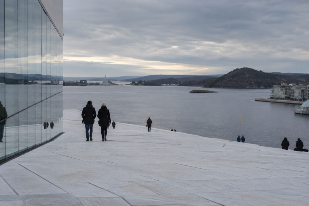 The sloping marble roof of the Oslo Opera House with the fjord behind
