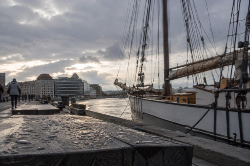 Wooden sailing ship moored at a Oslo pier under grey rainy sky