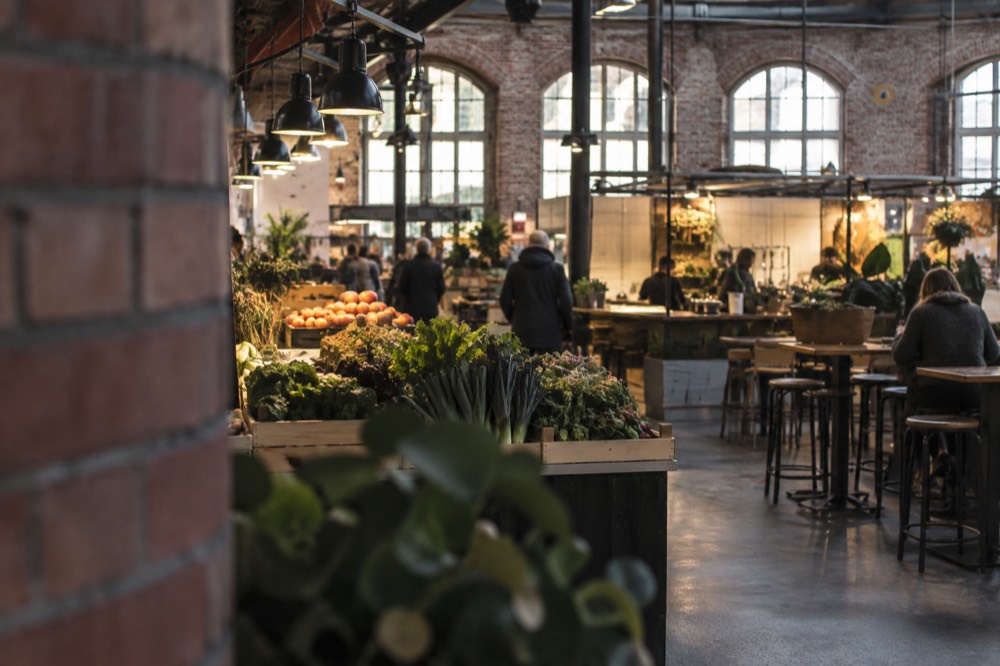 Indoor food hall with food stalls, shared tables and warm lighting