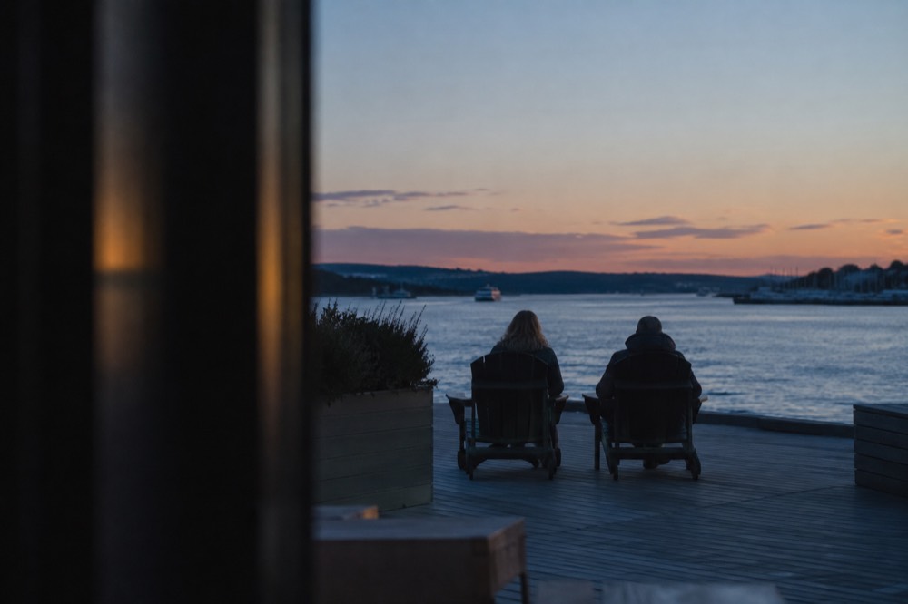 Two chairs facing the Oslofjord at sunset near the Aker Brygge waterfront