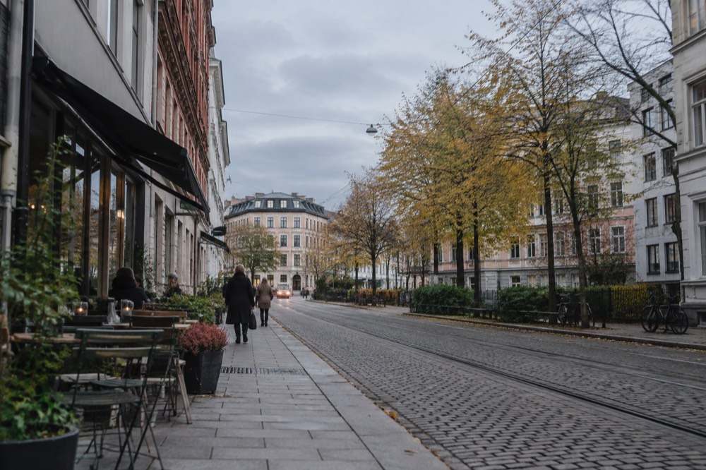 Cobblestone street in Grünerløkka with café tables and autumn trees
