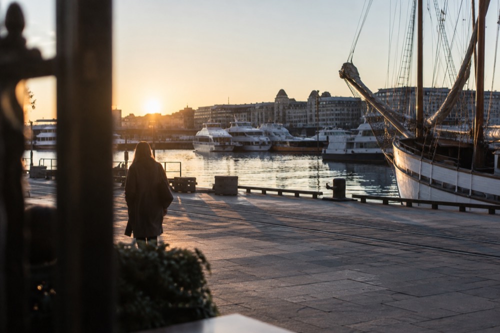 Wooden sailing ship and electric boats moored at the Oslo waterfront in evening light
