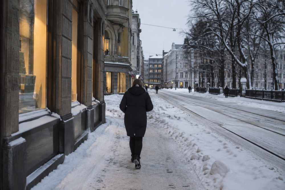 Snow-covered street with warm light from shop windows in winter