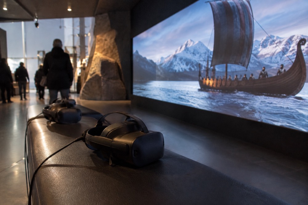 A dim museum gallery with a glowing Viking-themed virtual reality screen