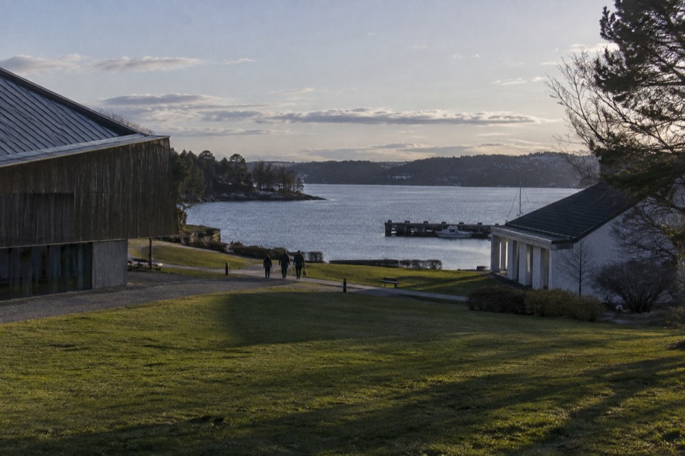 Museum buildings and green lawns on the Bygdøy peninsula beside calm harbor water