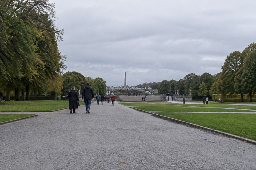 Morning light over open lawns and stone paths in Vigeland sculpture park with visitors strolling